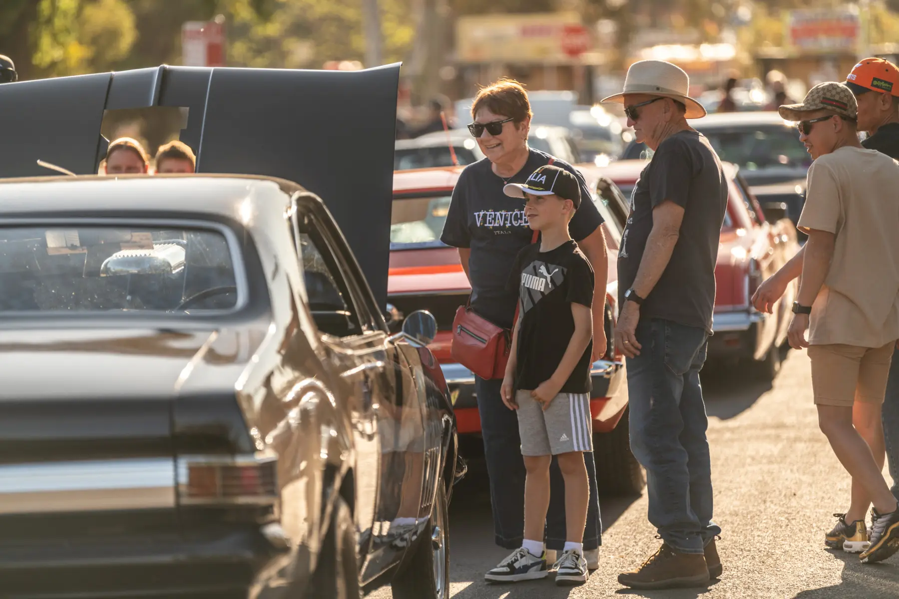 Family enjoying a classic car display in the evening light